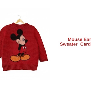 Op de afbeelding: Rood vest met Mickey Mouse-ontwerp. Het kledingstuk hangt aan een houten hanger. De tekst "Mouse Ears Sweater Cardigan" is in de afbeelding opgenomen.
