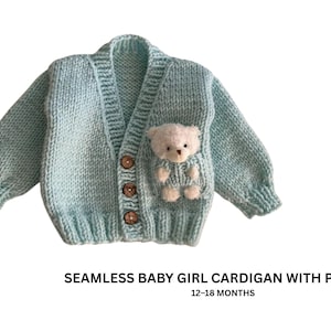 Op de afbeelding: Een lichtblauwe gebreide babycardigan met een teddybeerzak. De cardigan heeft drie houten knopen en is ontworpen voor baby's van 12-18 maanden. De tekst op de afbeelding luidt: SEAMLESS BABY GIRL CARDIGAN WITH POCKET.