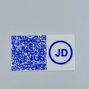 Puede incluir: Una pegatina blanca con un código QR azul y un círculo azul con las letras "JD" dentro.