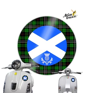 May include: A white scooter with a round sticker featuring the Scottish flag and a thistle emblem. The sticker is set against a green, black, and red tartan background. The Mia Buzz logo is visible.