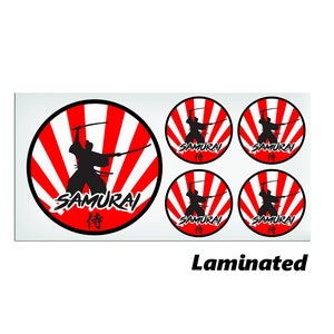 May include: Set of four laminated round stickers featuring a black silhouette of a samurai warrior holding swords against a red and white sunburst background. The text "SAMURAI" and the Japanese character for "faith" are printed in black on the stickers.