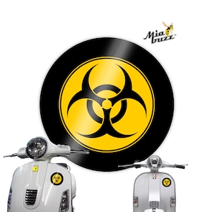 May include: A round black and yellow biohazard sticker featuring a biohazard symbol. The sticker is displayed on a white scooter. The image also shows a second white scooter with the same sticker.