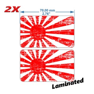 Puede incluir: Dos pegatinas de bandera japonesa del sol naciente roja y blanca con un aspecto desgastado. Cada pegatina mide 70 mm de ancho y está etiquetada como "laminated".