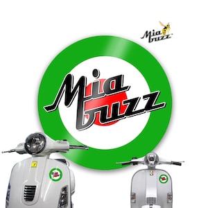 May include: White scooter with the "Mia Buzz" logo, featuring a green and red target design. The logo also includes a stylized bee. The scooter has a round headlight and a small logo sticker on the front.