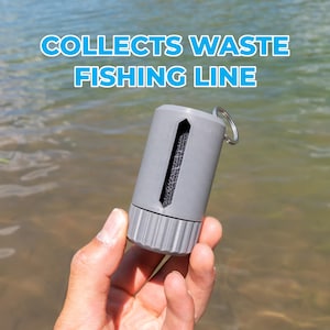 May include: A gray cylindrical fishing line waste collector featuring a vertical slot with a textured interior and a metal keyring attachment. The text "COLLECTS WASTE FISHING LINE" is displayed above the device in bold blue letters.