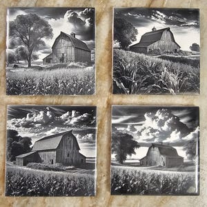 May include: Set of four black and white square coasters featuring a vintage barn in a field of corn. The barn is a classic red barn with a white roof and a large door. The cornfield is in the foreground and the barn is in the background. The sky is cloudy and the image is in black and white.