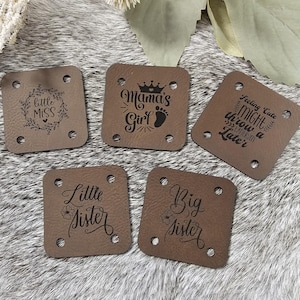 May include: Five brown leather patches with different sayings. The sayings are "Little Miss", "Mama's Girl", "Feeling Cute Might Throw a Later", "Little Sister", and "Big Sister".
