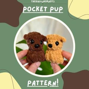 May include: Two small, crocheted dog toys, one brown and one tan, are held in front of a green and brown background. The toys have black eyes and noses. The text "POCKET PUP" and "PATTERN!" are displayed.