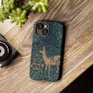 May include: A smartphone case featuring a dark forest-themed illustration with two deer standing among dense green foliage, leaves, and small orange flowers. The design covers the entire back of the case, including the area around the camera lens.