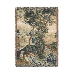 May include: Woven tapestry throw blanket featuring a pastoral landscape with trees, foliage, and birds in shades of green, blue, and beige. The blanket has a fringed edge in a reddish-brown color. A decorative home textile.