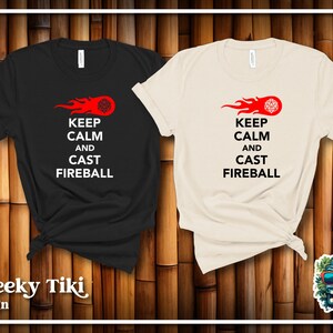 May include: Two t-shirts with a black and white design. The design features a red flame with a black 20-sided die at the end of the flame. The text on the shirts reads "Keep Calm and Cast Fireball".