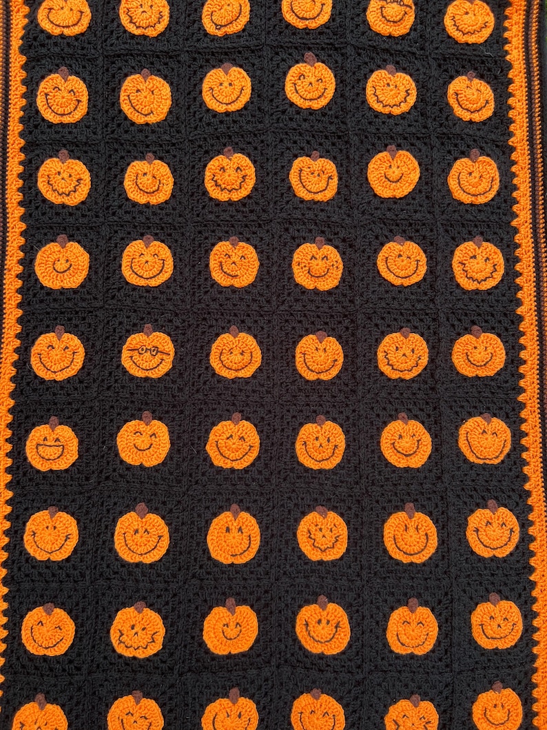 May include: A black and orange crocheted blanket featuring a repeating pattern of smiling orange pumpkins. The blanket has an orange border and is perfect for Halloween or autumn decor.