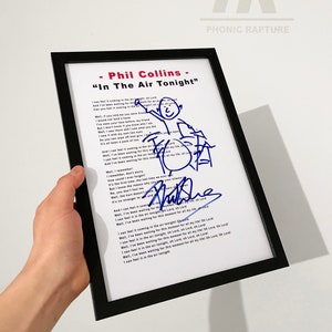 Peut inclure: Impression encadrée des paroles de "In The Air Tonight" de Phil Collins, avec une illustration et une signature bleues. Le cadre noir entoure l'impression blanche, tenue par une main sur fond blanc. Le texte "Phonic Rapture" est en haut à droite.