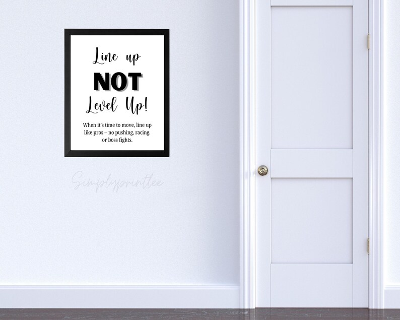 May include: A framed black and white print with the text "Line up NOT Level Up!". The print includes the text "When it's time to move, line up like pros - no pushing, racing, or boss fights."