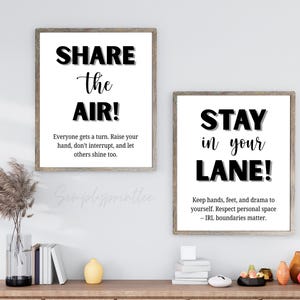 May include: Two framed wall art prints with inspirational quotes. The first reads "SHARE the AIR!" and the second says "STAY in your LANE!". Both prints have a white background with black text and are in wooden frames.