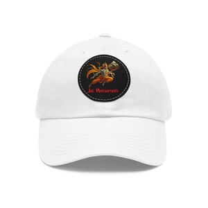 May include: White baseball cap with a black and white circular patch featuring a cartoon image of a monkey holding a rock. The text "Jai Hanuman" is written in red below the image.