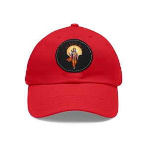 May include: Red baseball cap with a black and white circular patch featuring a figure in a yellow and orange outfit with the text "Jai Shree Ram".