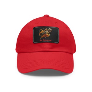 May include: Red baseball cap with a black and white patch featuring a cartoon image of a Hindu deity, Hanuman, with the text "Jai Hanuman".
