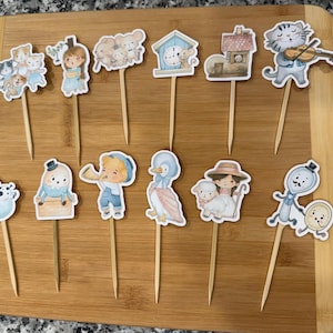 May include: A set of 12 cupcake toppers featuring various characters from the children's book 'The Very Hungry Caterpillar'. The toppers are printed on cardstock and feature a variety of colours, including blue, green, yellow, red, and orange. The toppers are perfect for adding a whimsical touch to any birthday party or special occasion.