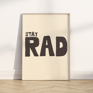 May include: A beige poster with black text that reads "Stay Rad". The text is in a bold, blocky font.