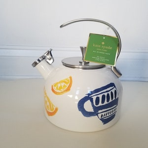 May include: White tea kettle with a stainless steel handle and lid. The kettle features orange slice and blue teacup designs. A green tag reads "kate spade NEW YORK ALL IN GOOD TASTE".