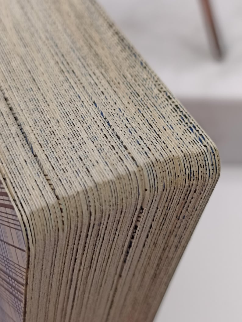 Puede incluir: Primer plano de una baraja de cartas con un aspecto texturizado y envejecido. Los bordes de las cartas son visibles, mostrando un efecto en capas con un color beige claro y l&iacute;neas oscuras. La esquina de la baraja revela un dise&ntilde;o estampado.