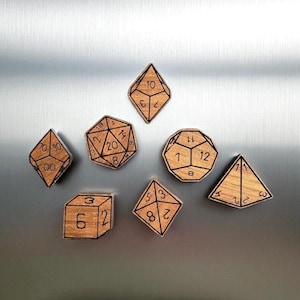 May include: A collection of wooden dice in various geometric shapes, including a cube, pyramid, and diamond. Each die is etched with numbers and has a natural wood grain finish. The dice are arranged on a metallic surface.
