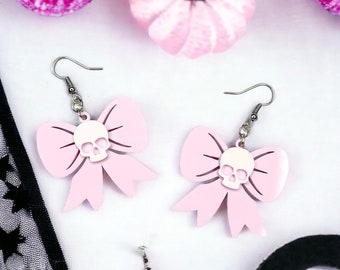 May include: A pair of pink bow earrings with a white skull charm in the center of each bow.