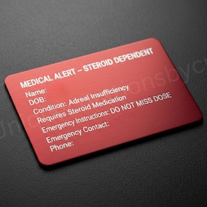 May include: A red medical alert card with white text. The card reads "MEDICAL ALERT - STEROID DEPENDENT" and includes fields for name, DOB, condition, emergency instructions, and contact information. The condition listed is Adreal Insufficiency.