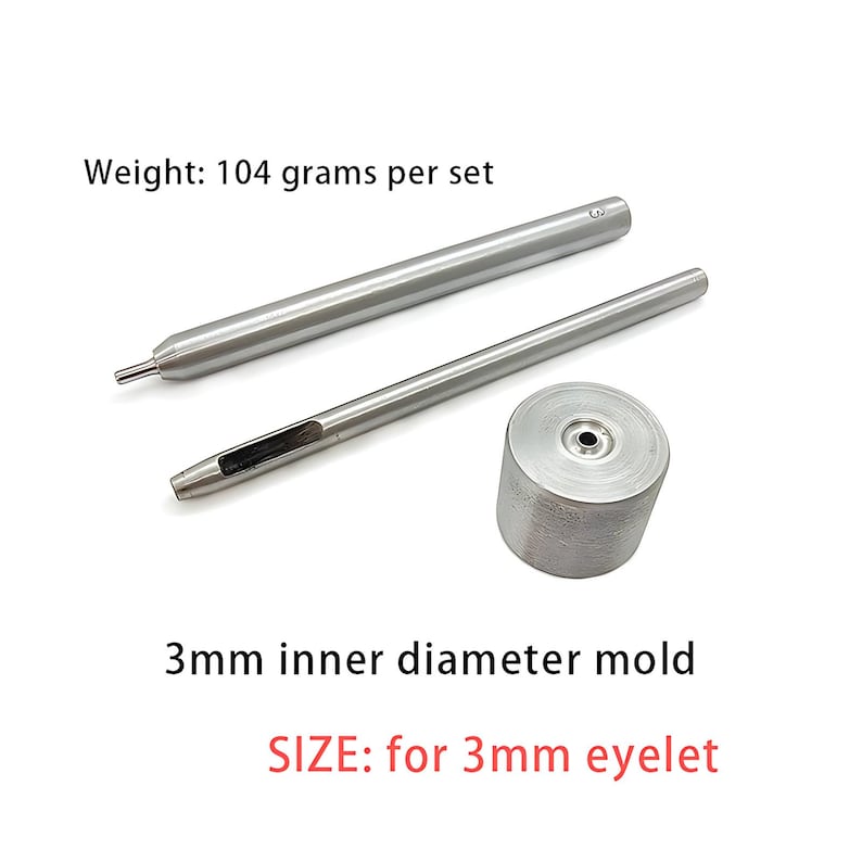 May include: A silver-colored metal eyelet setting tool set consisting of two long cylindrical punches and one circular base mold. The set weighs 104 grams and is designed for 3mm eyelets, featuring a 3mm inner diameter mold for precise application.