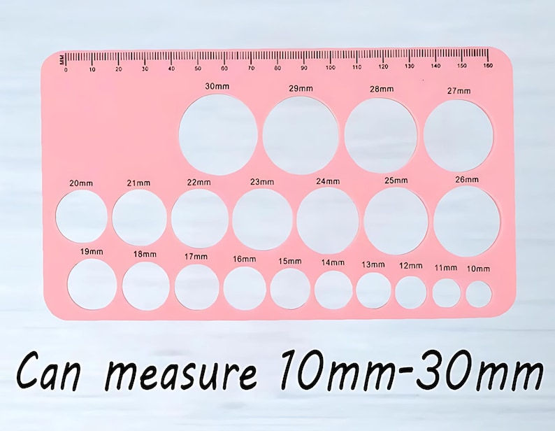 May include: Pink plastic ruler with a series of circles of different sizes, ranging from 10mm to 30mm in diameter. The ruler has a scale marked in millimeters.