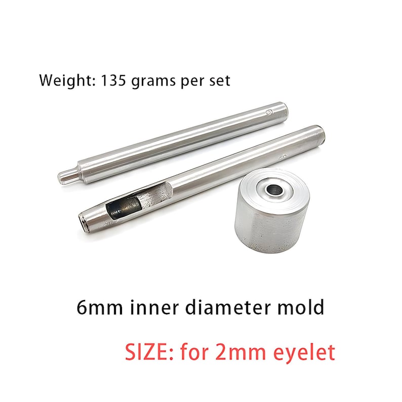May include: A silver-colored metal eyelet setting tool set consisting of two long cylindrical punches and one circular base die. The text reads Weight: 135 grams per set, 6mm inner diameter mold, and SIZE: for 2mm eyelet.