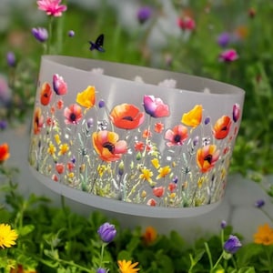 May include: A white ceramic planter with a floral design featuring red, orange, yellow, and pink poppies. The planter has a round shape and a smooth, glossy finish.