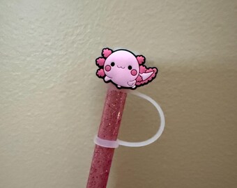 May include: A pink glitter straw with a pink axolotl charm attached to the top. The charm has a white loop for attaching to the straw.
