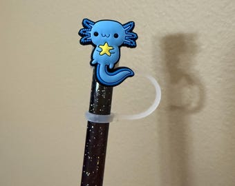 May include: A blue axolotl pencil topper holding a yellow star. The topper is attached to a black glitter pencil with a clear plastic pencil holder.