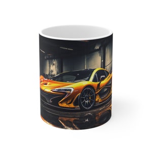 May include: A white ceramic mug with a full color image of a bright yellow sports car in a dark garage setting. The car is a McLaren P1.