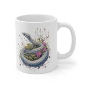 May include: White ceramic mug with a graphic of a gray snake curled up in a bed of green and brown foliage with pink flowers.
