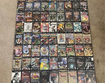 May include: A collection of 64 GameCube video game cartridges, arranged in rows on a gray surface. The cartridges are black with colorful labels featuring various game titles, including "Sonic Adventure 2", "Metroid Prime", "Zelda", "Super Smash Bros. Melee", and "Pikmin".