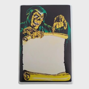May include: A rectangular sticker depicting a skeletal figure in a green hooded robe, pointing at a blank scroll. The figure has yellow skin and a sinister grin. The scroll is yellow with a white centre, set against a black background.