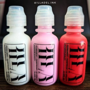 May include: Three small bottles of white, pink, and red ink. Each bottle has a black label with the text "ILLADEL.INK" and "PERMANENT/FADEPROOF/2X OPACITY SUPERIOR QUALITY" printed on it.