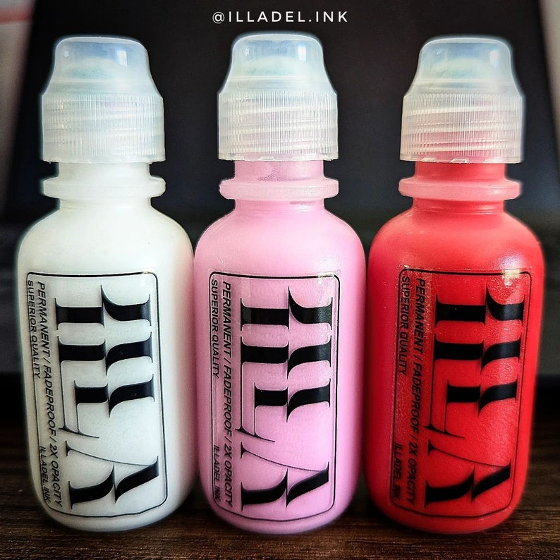 May include: Three small bottles of white, pink, and red ink. Each bottle has a black label with the text "ILLADEL.INK" and "PERMANENT/FADEPROOF/2X OPACITY SUPERIOR QUALITY" printed on it.