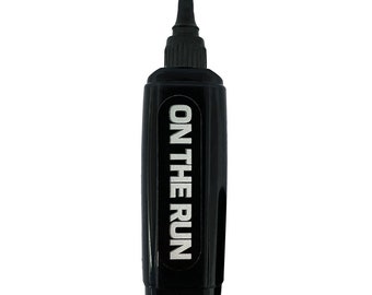 May include: A black bottle with a long, slender body and a pointed tip. The text "ON THE RUN" is printed in white on the front of the bottle. The bottle has a small, gold-colored nozzle.