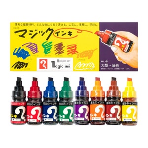 May include: A collection of eight Magic Ink markers in a range of colours, including black, red, blue, green, violet, orange, brown, and yellow. The markers are in clear bottles with black tips and Japanese text. A yellow box with Japanese text is also present.