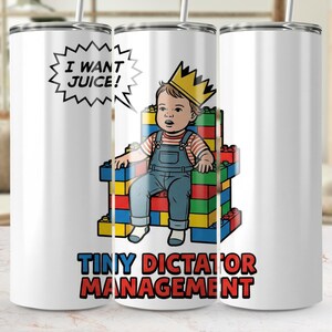 以下が含まれることがあります： 王冠をかぶり、カラフルなブロックで作られた玉座に座る漫画の赤ちゃんが描かれた白いタンブラー。「I WANT JUICE!」と「TINY DICTATOR MANAGEMENT」の文字が入っています。
