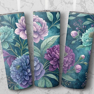 Op de afbeelding: Drie roestvrijstalen bekers met een bloemenontwerp. De bekers hebben een teal achtergrond met bloemen in aquarel-stijl in tinten paars, blauw en teal. Groene bladeren en stelen maken het ontwerp compleet.