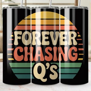 Puede incluir: Juego de tres vasos de acero inoxidable negro con un diseño retro. El diseño presenta el texto "FOREVER CHASING Q'S" en crema, naranja y verde, sobre un fondo estilo puesta de sol. Cada vaso tiene una pajita plateada.