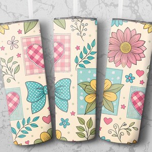 May include: Three insulated tumblers with a cream background and a patchwork design. Each tumbler features hearts, bows, and flowers in pink, blue, and yellow. The design includes floral and leaf accents.