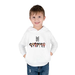 May include: A white hooded sweatshirt with a graphic of seven cartoon figures and the text "Tiny Tan". The sweatshirt has long sleeves and a front pocket. The figures are in various colours.