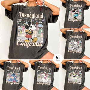 Peut inclure: T-shirts gris fonc&eacute; avec des graphiques Disneyland. Les chemises pr&eacute;sentent divers personnages Disney, dont Mickey Mouse, Minnie Mouse, un Stormtrooper, Eeyore, Marie et Buzz Lightyear, avec le texte "Disneyland California Est. 1955".