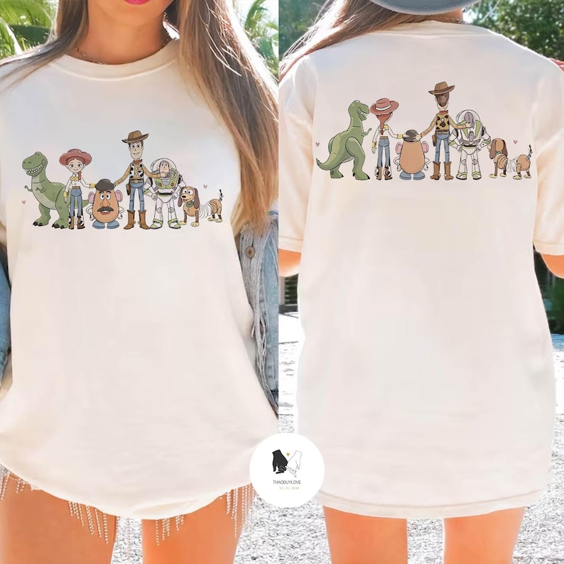 Peut inclure: T-shirt cr&egrave;me avec une illustration de personnages de dessin anim&eacute; populaire. L'avant et l'arri&egrave;re du t-shirt pr&eacute;sentent le m&ecirc;me motif. Le t-shirt a des manches courtes et un col rond.